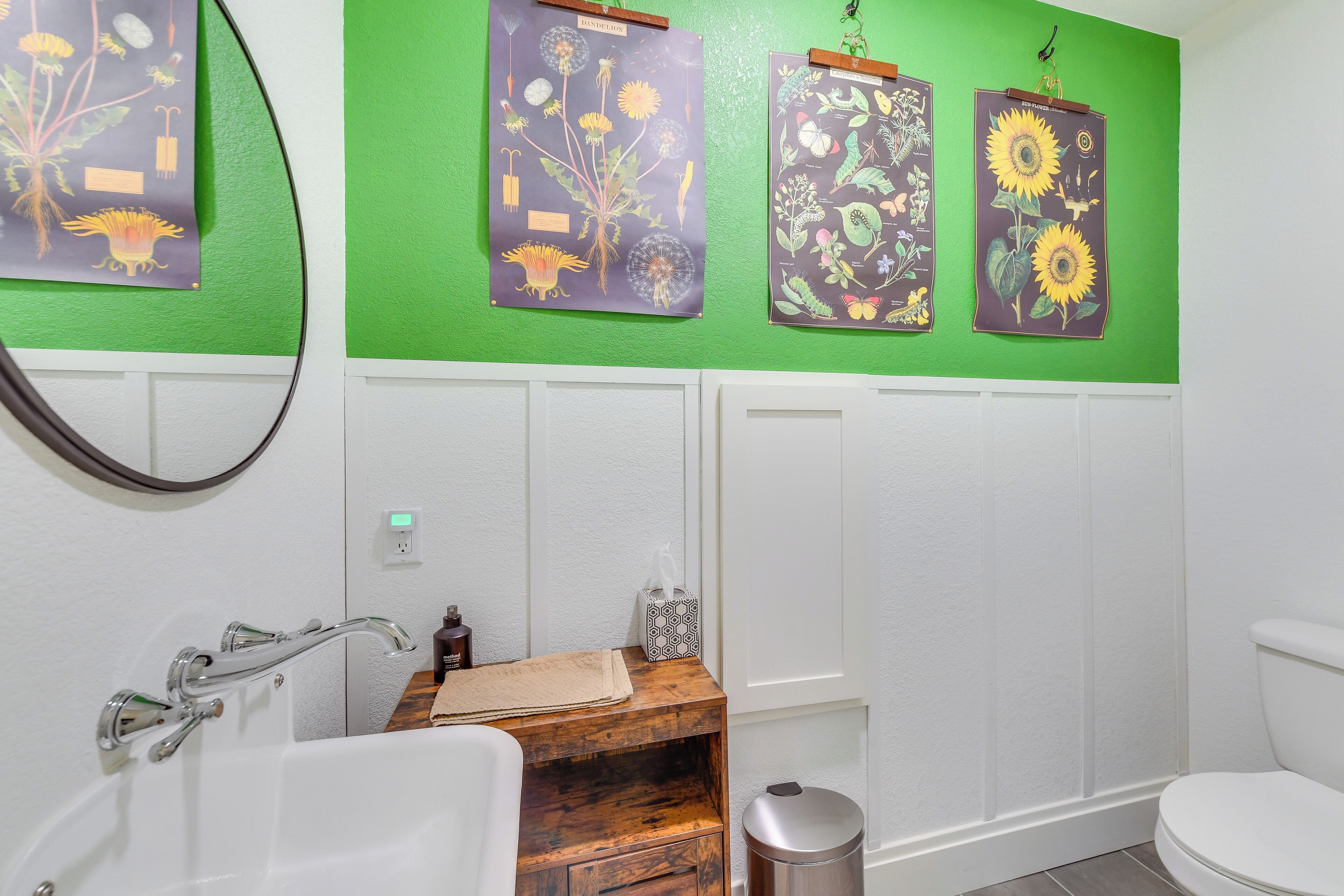 Un baño con pared verde, bañera blanca, tocador de madera y un inodoro.
