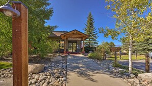 A lodge entrance with a wooden facade, a clear sky, and a pathway lined with rocks and plants. - Cozy & Chic Mountain Condo w/ Community Perks (Fraser)