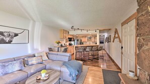 A modern living room with a sofa, coffee table, and a kitchen in the background. - Cozy & Chic Mountain Condo w/ Community Perks (Fraser)