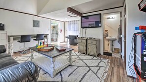 Una sala moderna con una mesa de comedor, dos sillones, un sofá y una zona de cocina con armarios y un lavabo.
