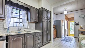 Una cocina con armarios de madera oscura, un refrigerador de acero inoxidable y una ventana con cortinas.