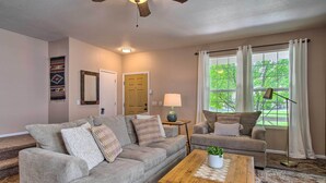 A living room with a sofa, coffee table, lamp, and a ceiling fan.