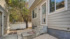 A house with a front porch, a small set of concrete steps leading to the door, and a tree in the background.