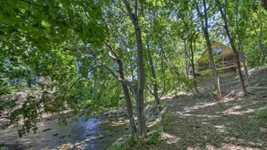 A cabin in a forested area with a stream nearby. - Kennebec River Cottage; 1/4 Mi to Boat Ramp! (Bath)