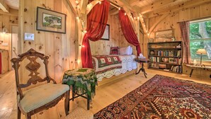 A cozy wooden cabin room with a bed, a chair, a small table, and a bookshelf. - Kennebec River Cottage; 1/4 Mi to Boat Ramp! (Bath)