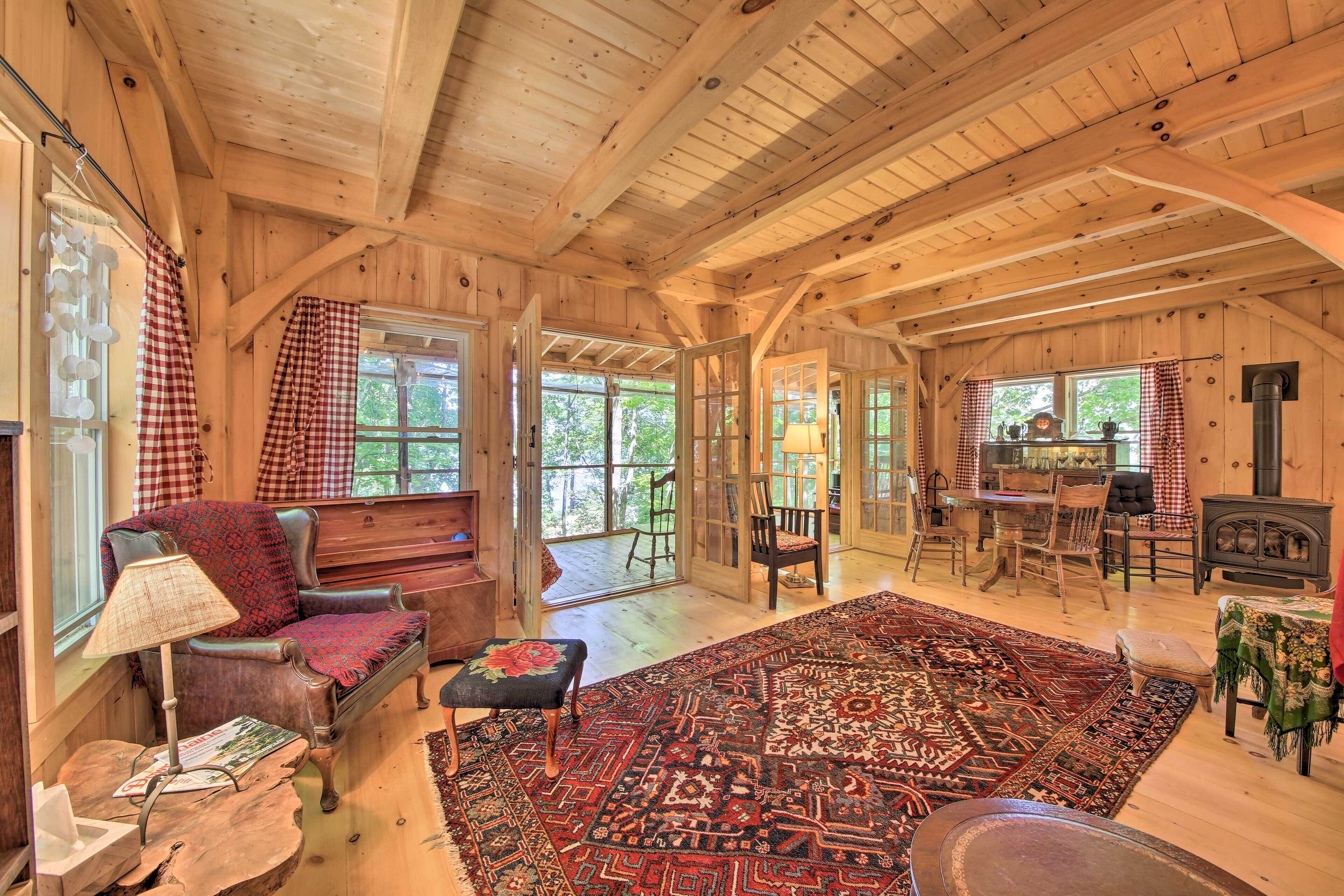 Interior acogedor de una cabaña con un gran techo de madera, una chimenea, un comedor y una sala de estar con alfombra y un banco.