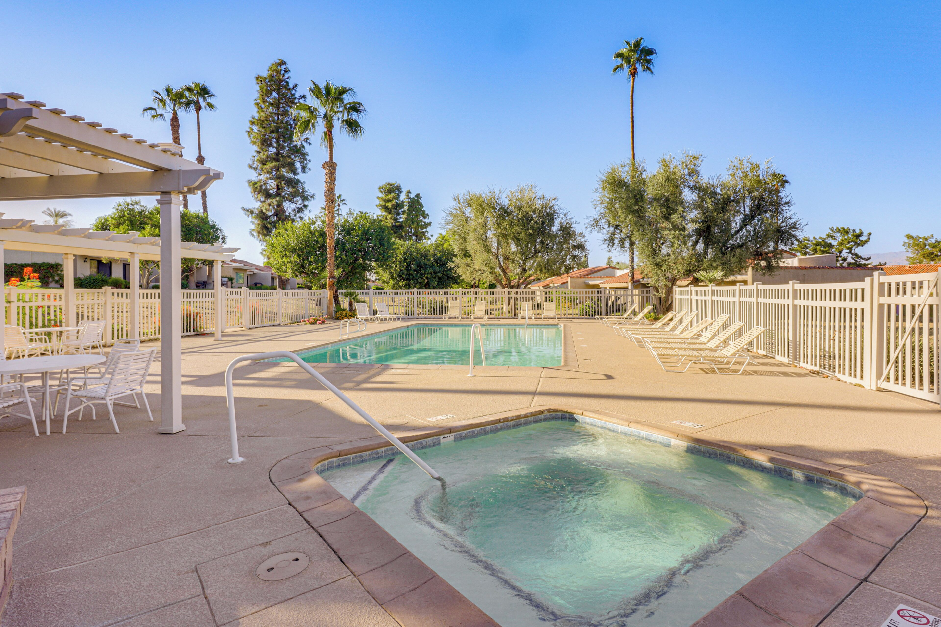 Un espace piscine comprenant un jacuzzi, des chaises longues et une pergola.