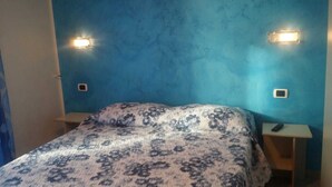 A bedroom with a bed, two bedside tables, and wall-mounted lights.