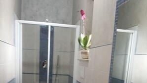 A bathroom with a glass shower enclosure, a toilet, a bathtub, and a sink.