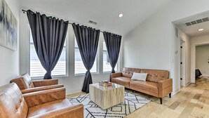 Ein modernes Wohnzimmer mit einem braunen Ledersofa, einem Holztisch und einem gemusterten Teppich.