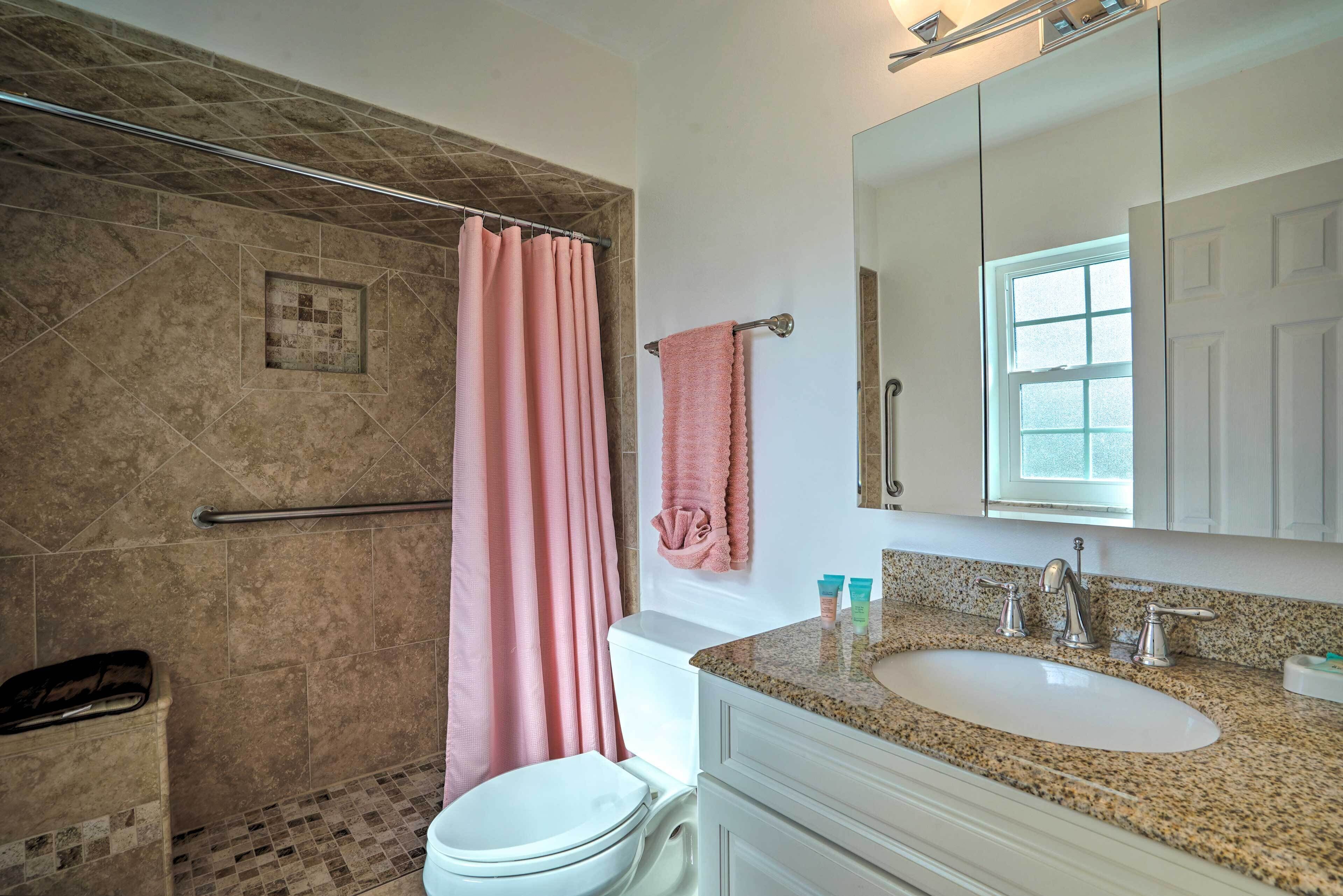 A bathroom with a shower, toilet, sink, and vanity.
