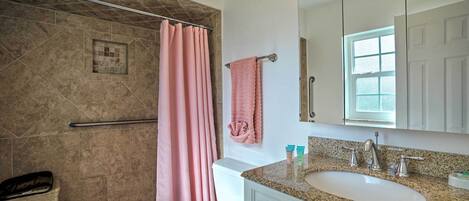 A bathroom with a shower, toilet, sink, and vanity.