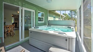 Een wellnessruimte met een jacuzzi, schuifdeuren en uitzicht op buiten.