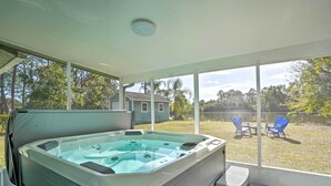 Een hottub in een overdekte buitenruimte met uitzicht op een achtertuin en een huis.