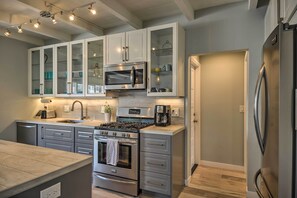 A modern kitchen with stainless steel appliances, grey cabinetry, and a central island. - Remodeled Ventura Beach Home With Yard & Fire Pit! (Ventura)