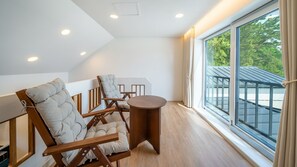 Una habitación moderna con un ventanal grande, una mesa de madera y dos sillones tapizados.