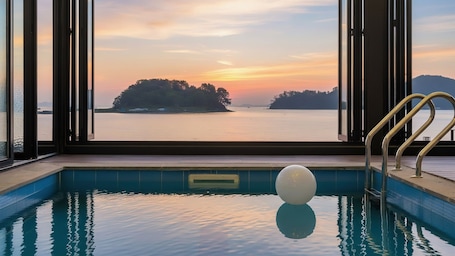 A pool with a view of a sunset over water and islands.. Changwon 055 Poolvilla