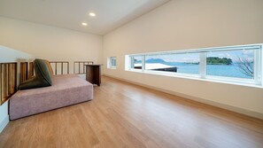 Una habitación amplia con un ventanal grande, una cama y un altavoz.