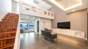 Un interior moderno con una escalera, un comedor, un televisor y vistas al exterior.