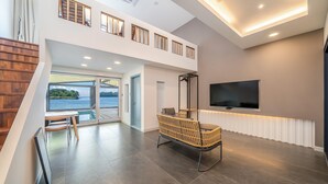 A modern interior with a TV, a wicker chair, a pool view, and a staircase. - Changwon 055 Poolvilla (Changwon)