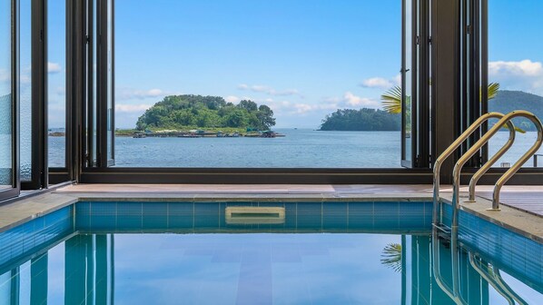 Une piscine avec vue sur une petite île et sur l’eau.