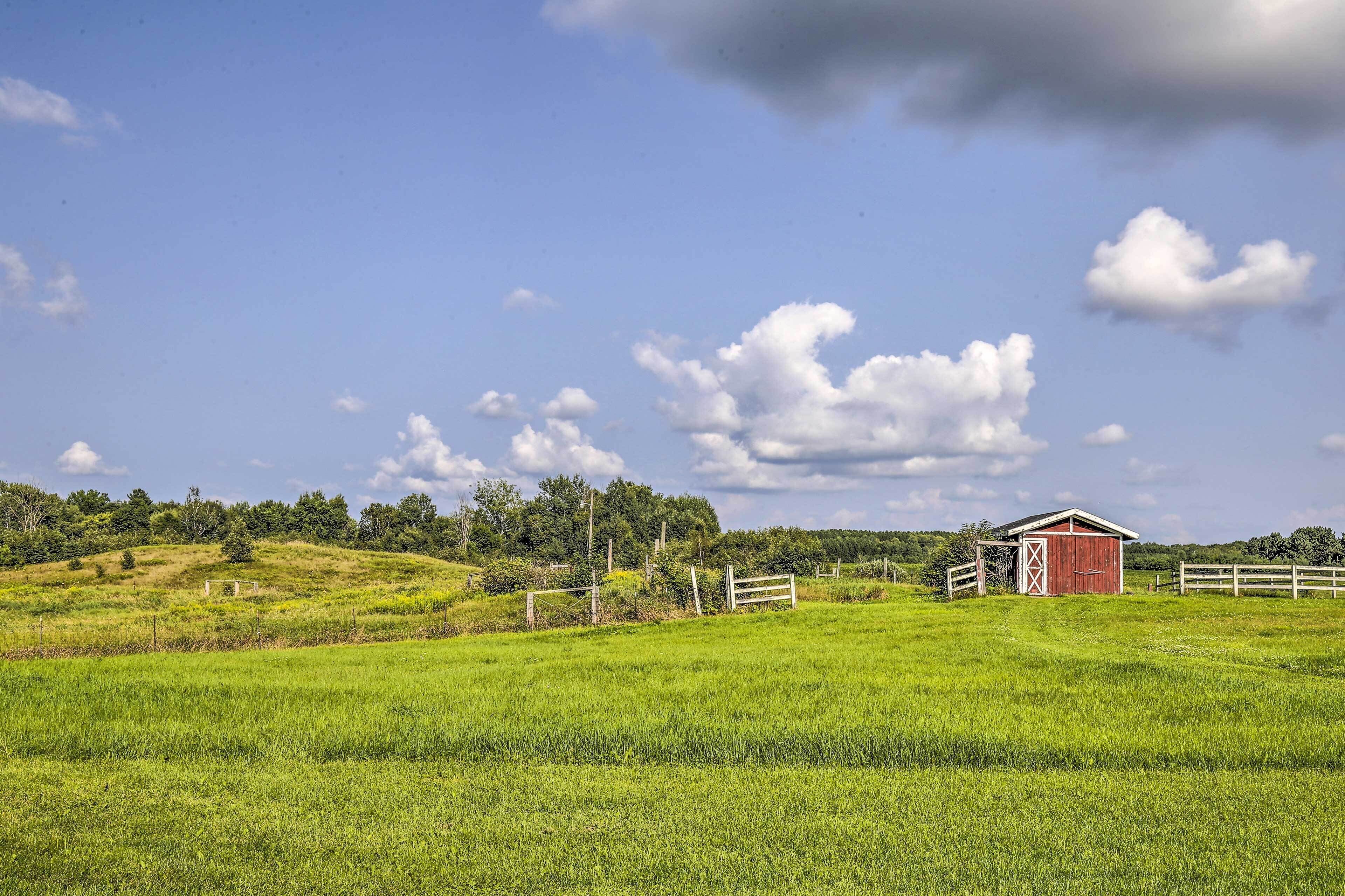 A red barn on a grassy hill with a clear sky.