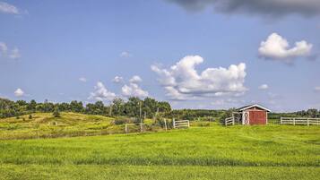 A red barn on a grassy hill with a clear sky.