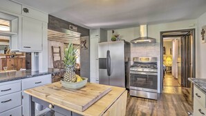 Una cucina moderna con frigorifero in acciaio inox, forno integrato e isola in legno con una ciotola di frutta.