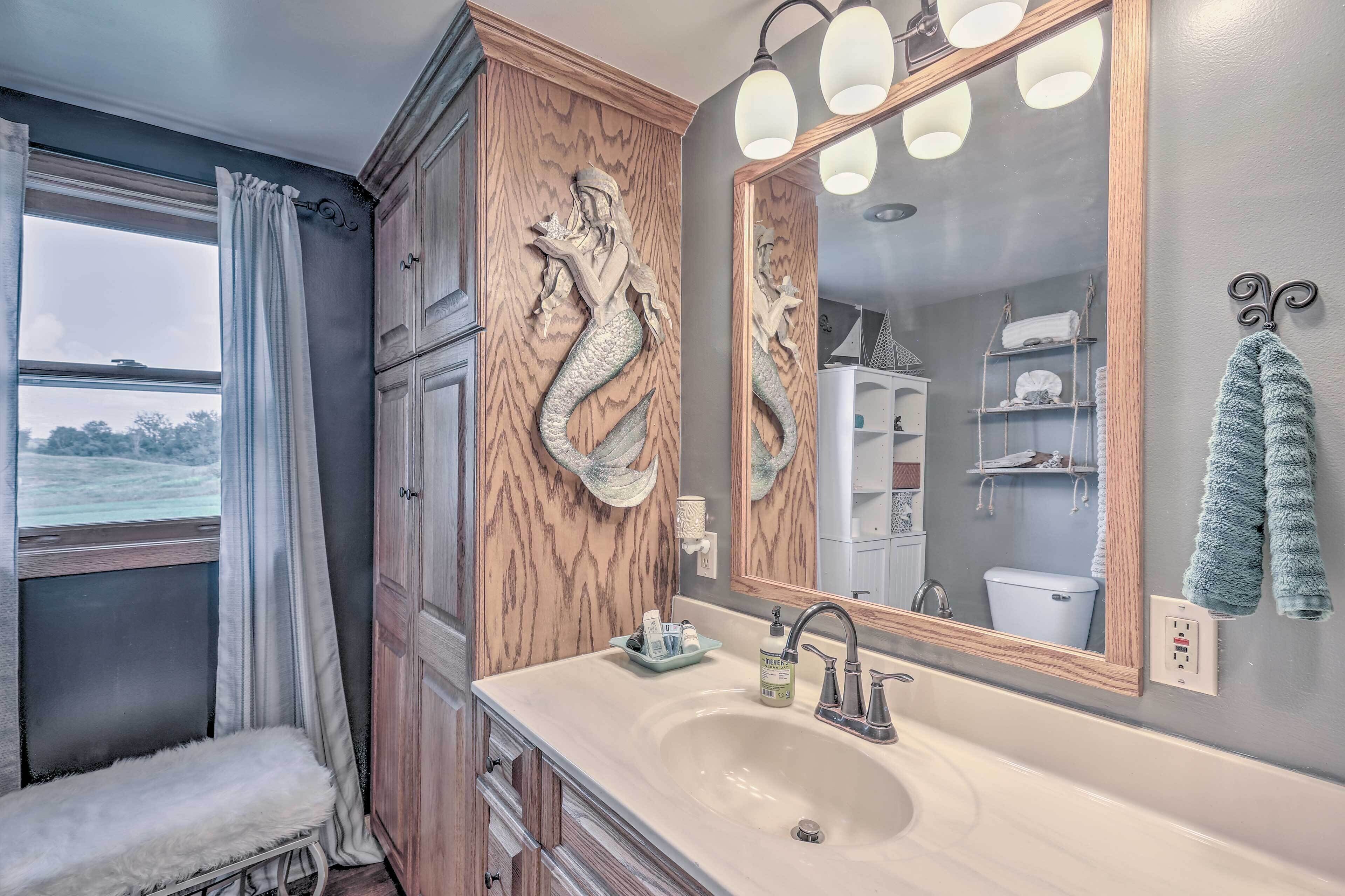 Un bagno con uno specchio grande, rivestimenti in legno, un lavandino e una panca.