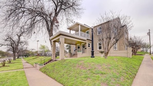 A two-story house with a balcony, a front porch, and a small front yard with grass and a tree. - 2 Mi to Dtwn: Waco Home w/ Shared Yard! (Waco)