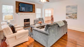 A living room with a fireplace, a ceiling fan, a flat-screen TV, and a painting on the wall. - 2 Mi to Dtwn: Waco Home w/ Shared Yard! (Waco)