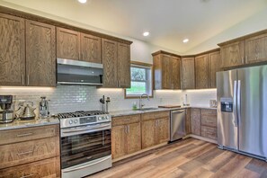 A modern kitchen with wooden cabinets, stainless steel appliances, and a herringbone-patterned backsplash. - Lake Home Near Alexandria: Kayaks Provided! (Brandon)