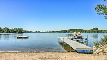 A calm lake with a dock extending into the water, surrounded by greenery.