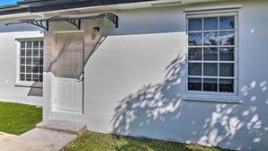 Une maison moderne avec une façade blanche, une porte d’entrée et deux fenêtres.