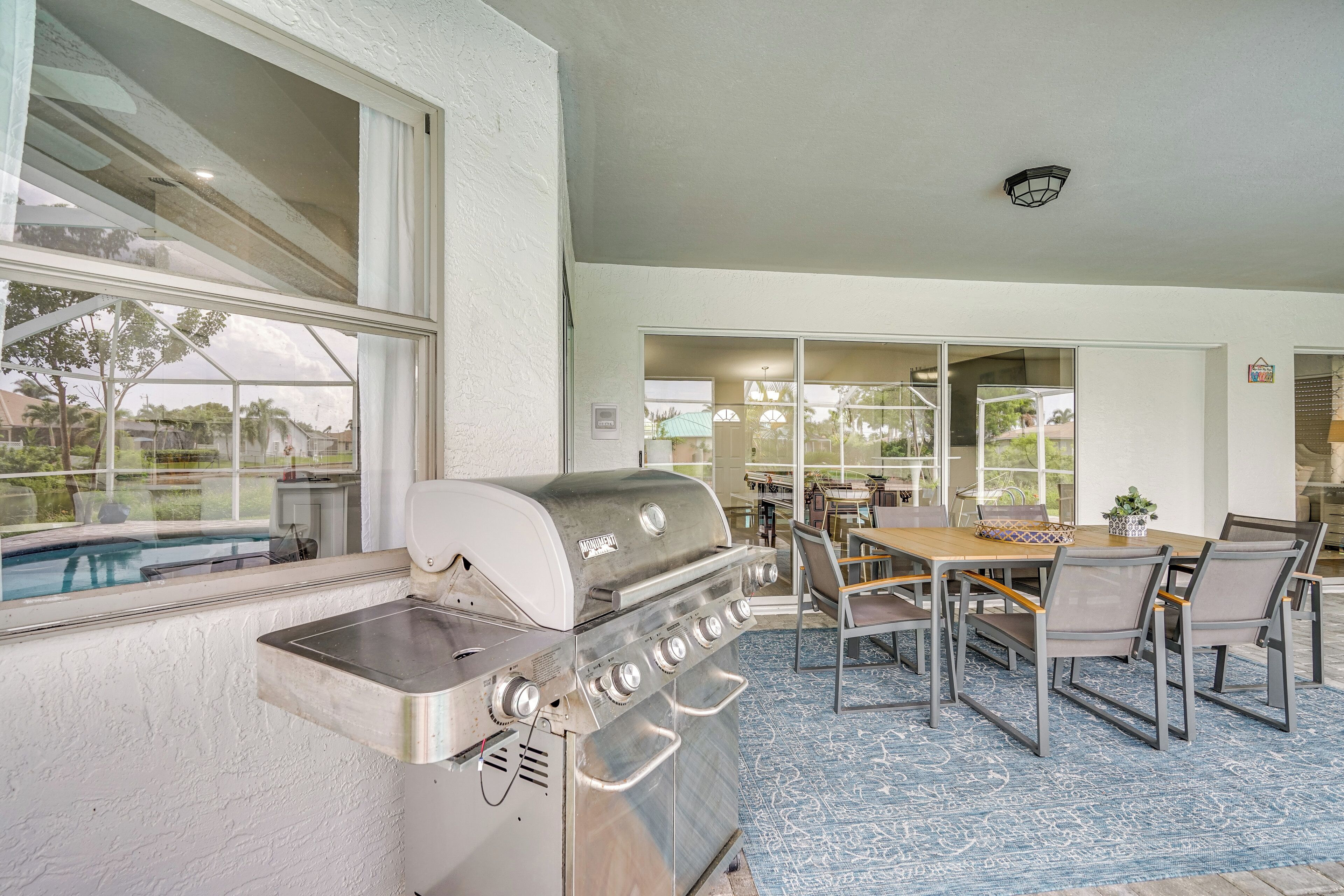 Eine Terrasse mit Grill aus Edelstahl, einem Esstisch mit Stühlen und Blick auf einen Swimmingpool.