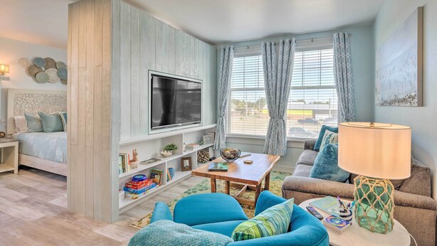 A modern living room with a TV, sofa, and a table with a lamp. - 1 Block to Long Beach! Adorable Downtown Studio (Long Beach)