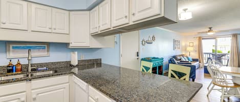 A kitchen with white cabinets, granite countertops, and a dining area with a table and chairs.