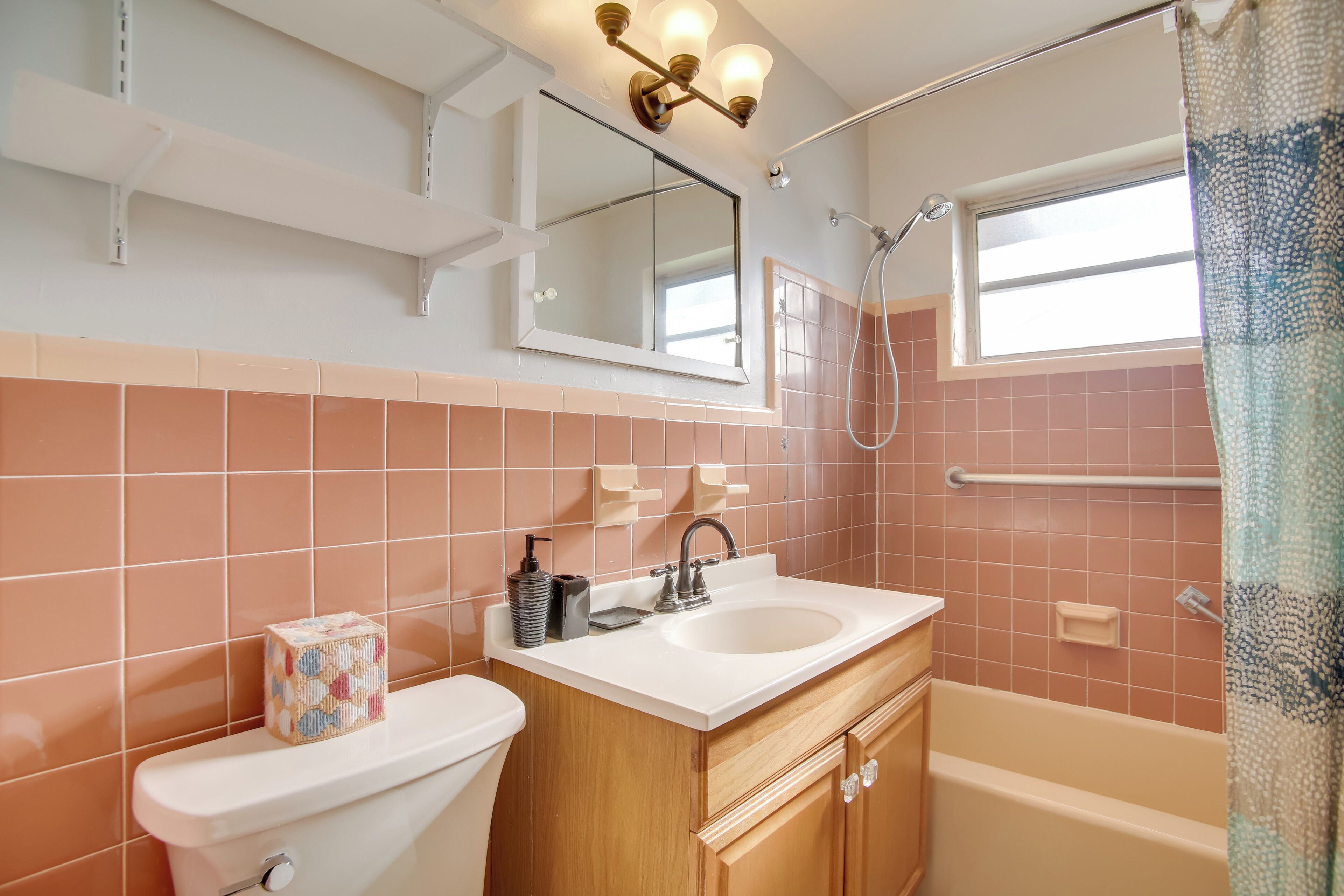 A bathroom with a toilet, sink, and bathtub. There is a mirror above the sink and a showerhead above the bathtub.