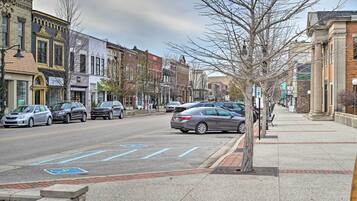 A street with parked cars, a sidewalk, and buildings with commercial establishments.