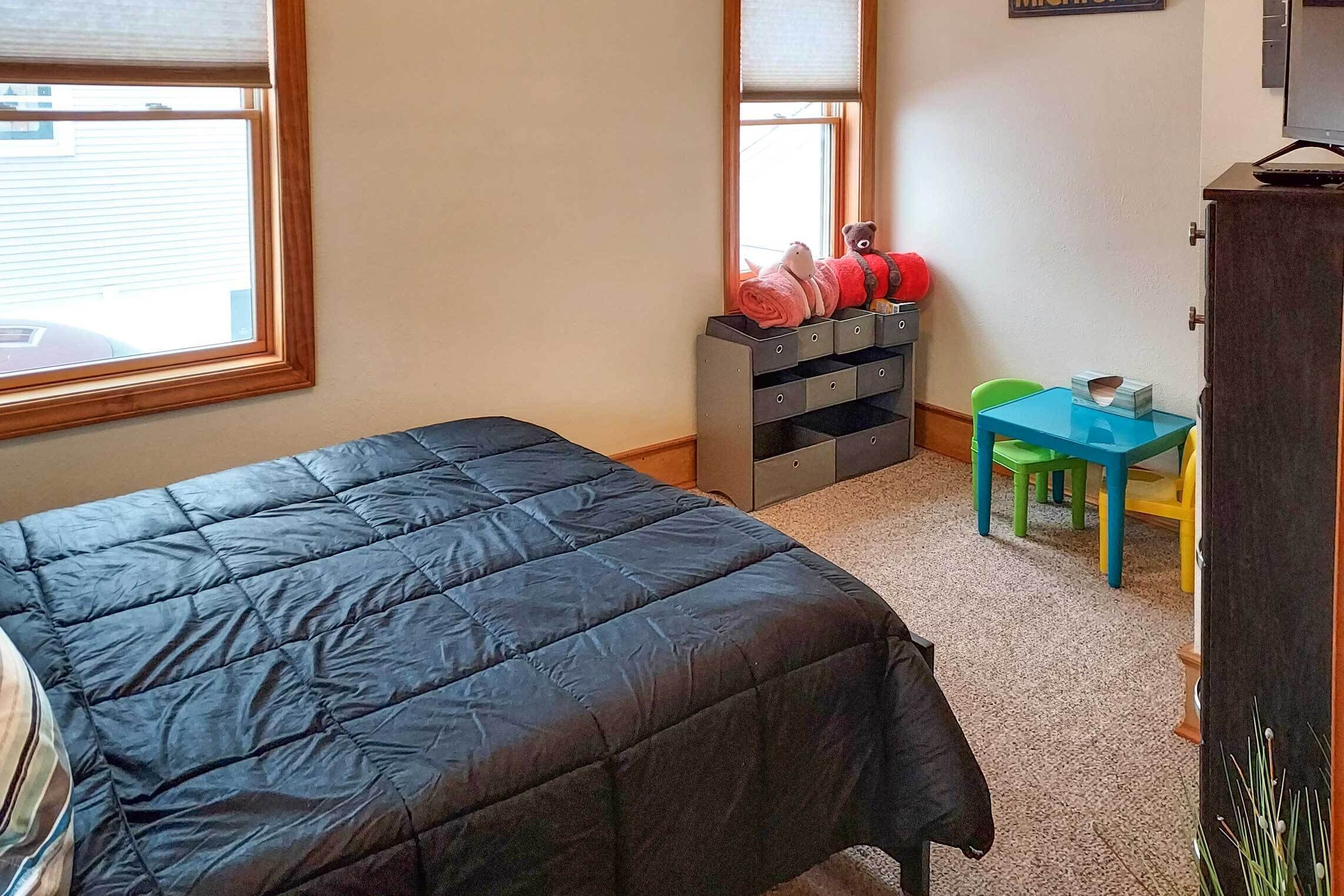 A bedroom with a bed, a desk, a chair, and a dresser.