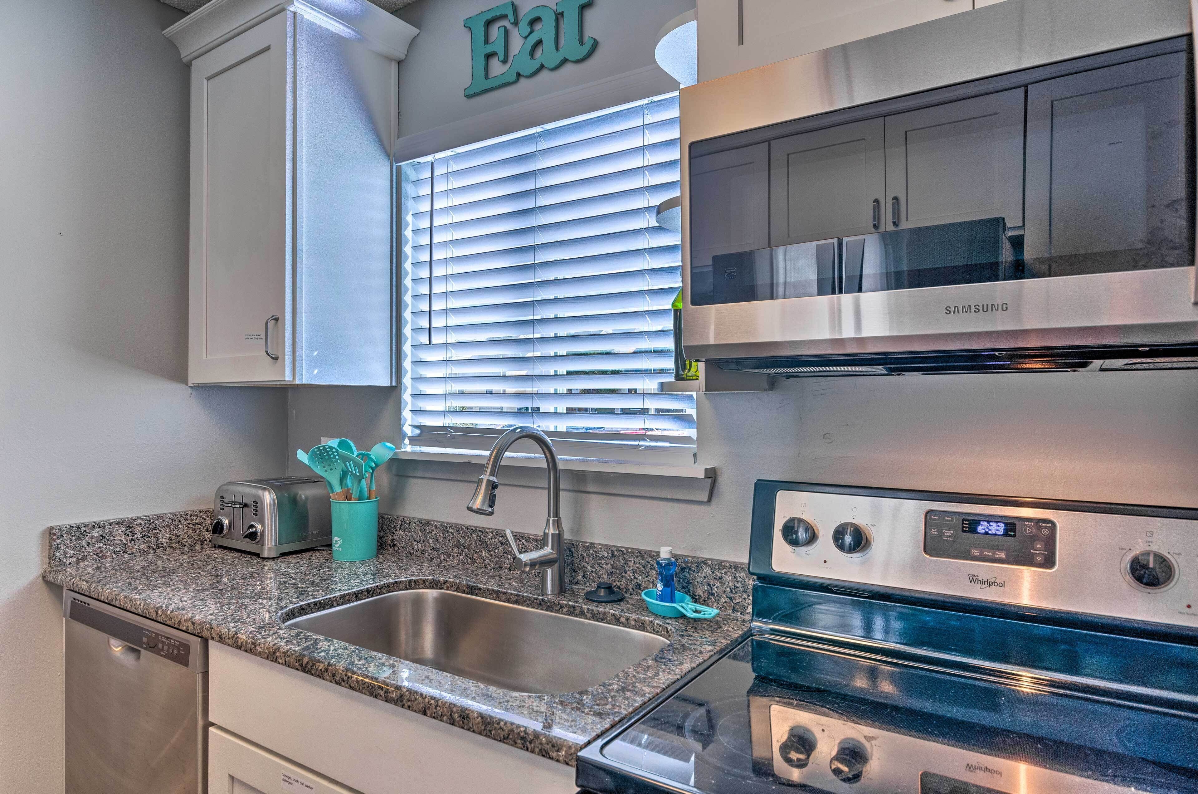 Una cocina moderna con lavavajillas de acero inoxidable, estufa Whirlpool y ventana con persianas.