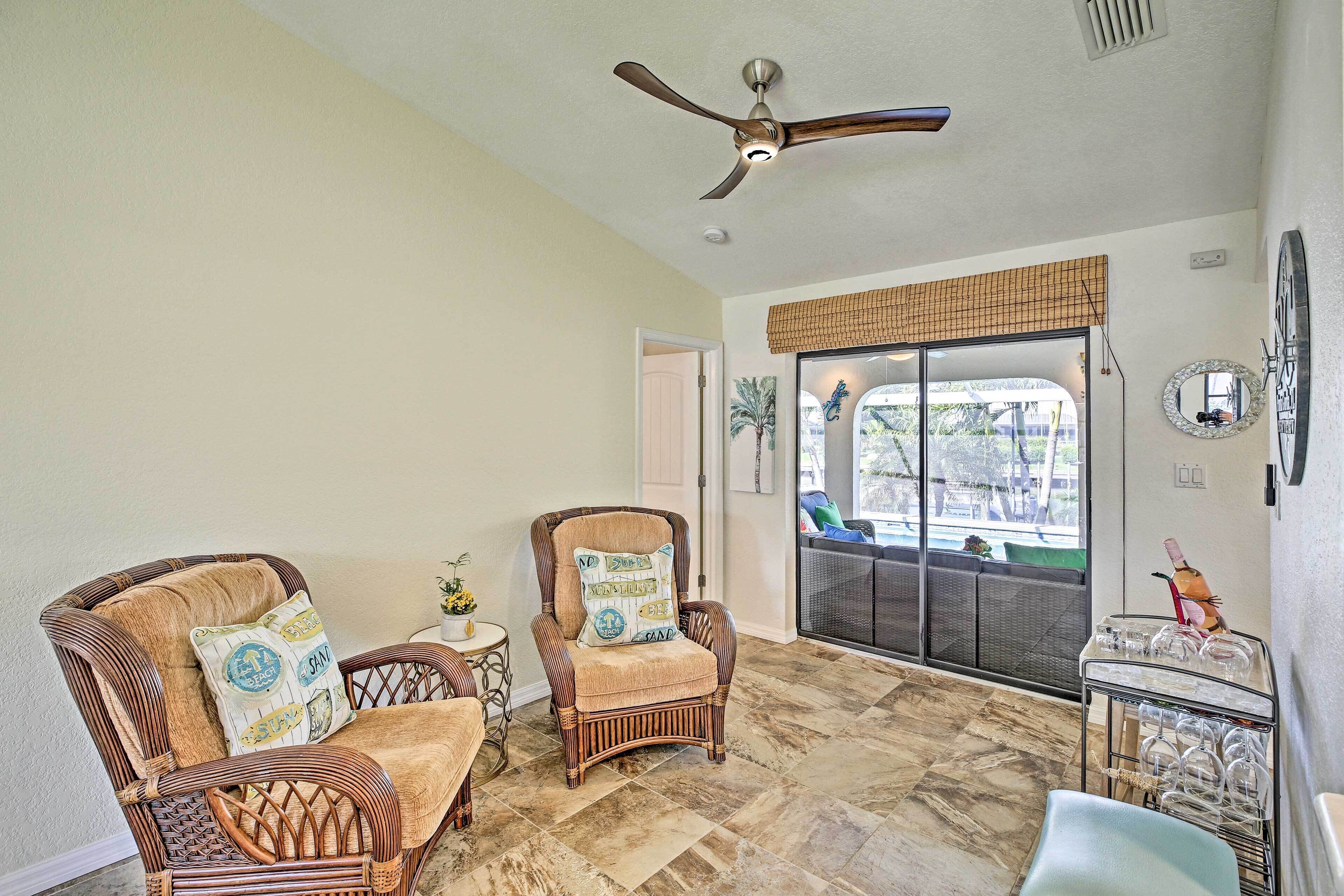 A room with wicker furniture, a ceiling fan, and a view through a glass door.