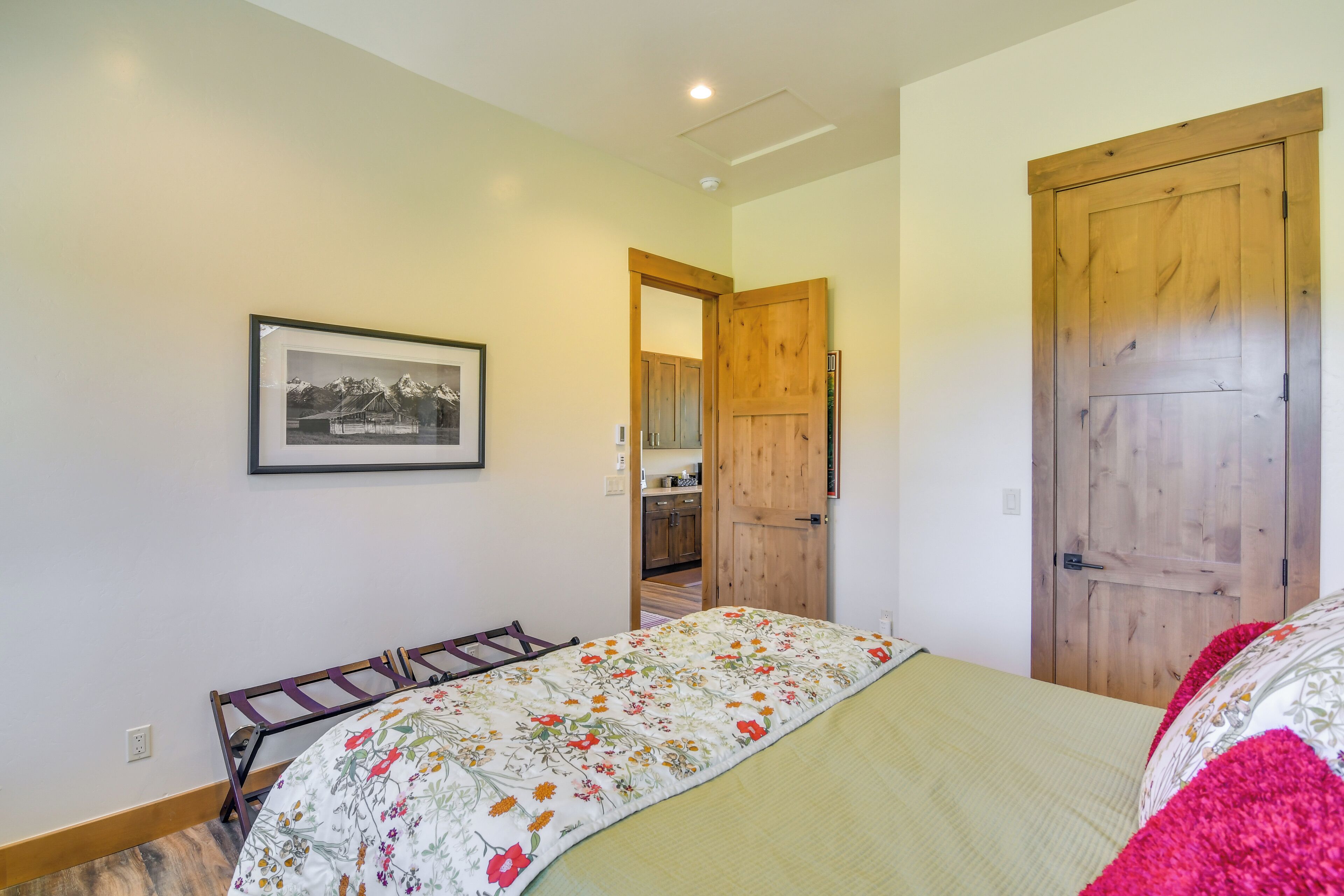 A bedroom with a bed, a wooden door, and a framed picture on the wall.