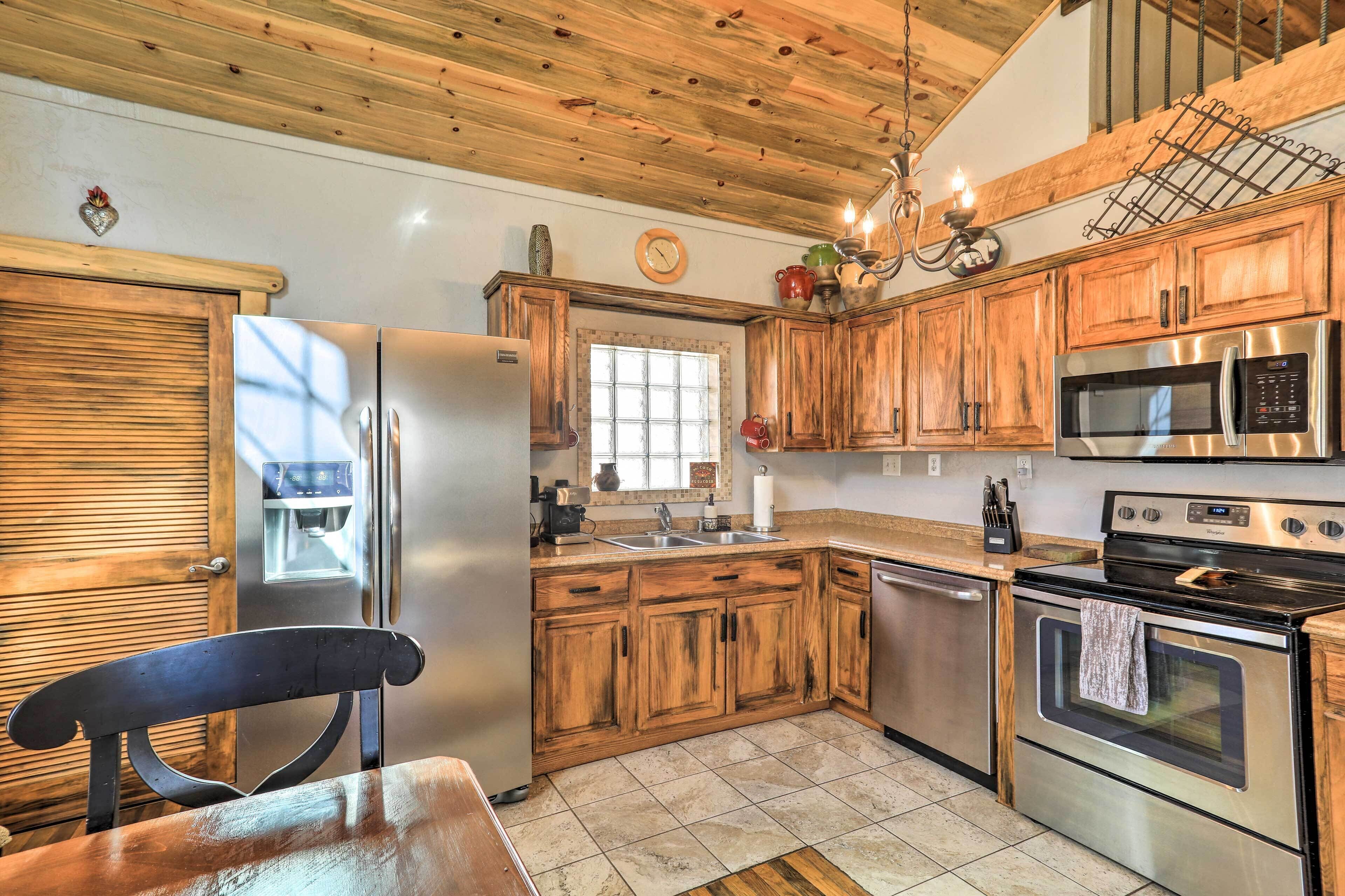 A kitchen with wooden cabinets, stainless steel appliances, a window, and a chandelier.