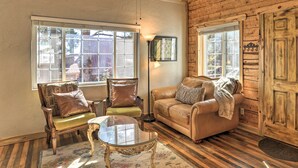 A cozy living room with a wooden ceiling, two leather sofas, a glass coffee table, and a large window. - Tasteful Log Cabin Retreat on Lake Pagosa! (Pagosa Springs)