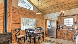 A rustic kitchen with wooden walls, a dining table with chairs, a stove, and a refrigerator. - Tasteful Log Cabin Retreat on Lake Pagosa! (Pagosa Springs)