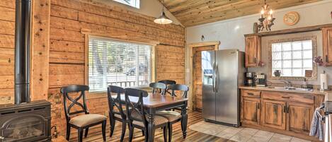 Una cocina rústica con paredes de madera, una mesa de comedor con sillas, una estufa y un refrigerador.