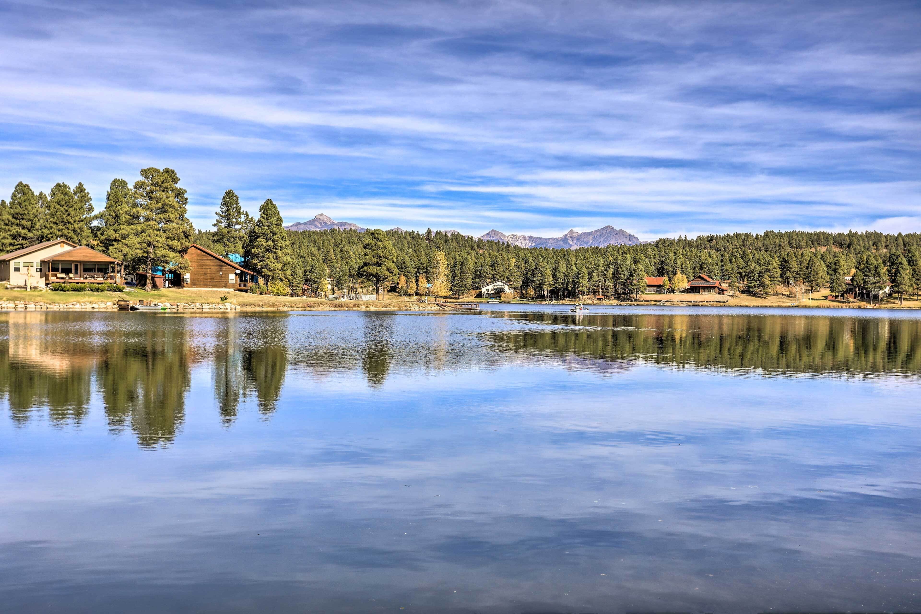 A lakeside property with cabins, a dock, and a forested backdrop.