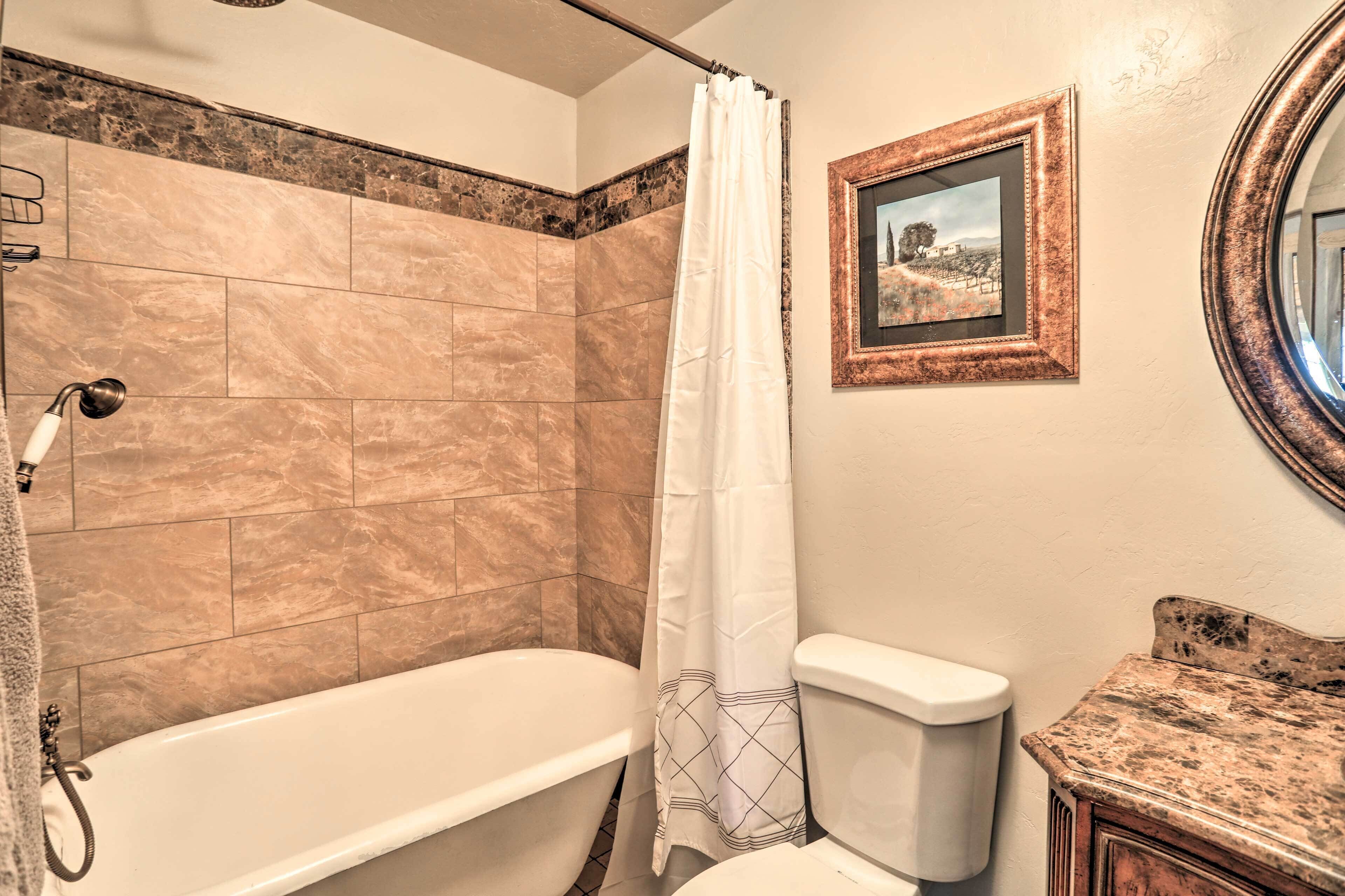 Een badkamer met een bad, toilet en een fotolijst aan de muur.