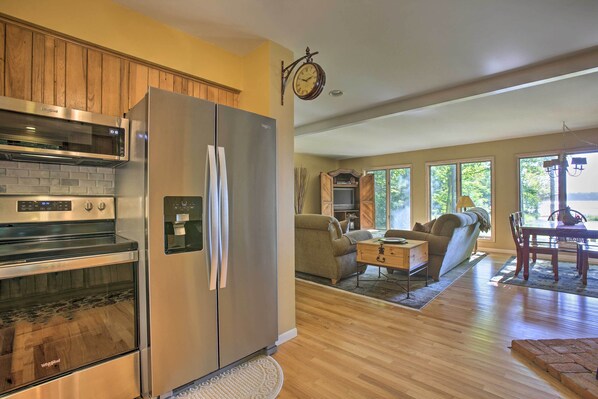 A modern kitchen with a stainless steel refrigerator, oven, and microwave. There is a dining area with a wooden table and chairs.
